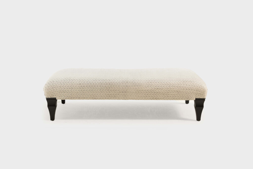 A luxury large rectangular footstool covered in a light chevron fabric -front